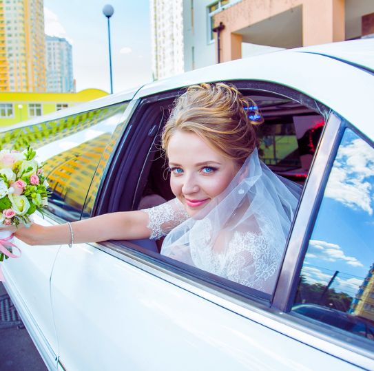 happy bride in limousine with flower
